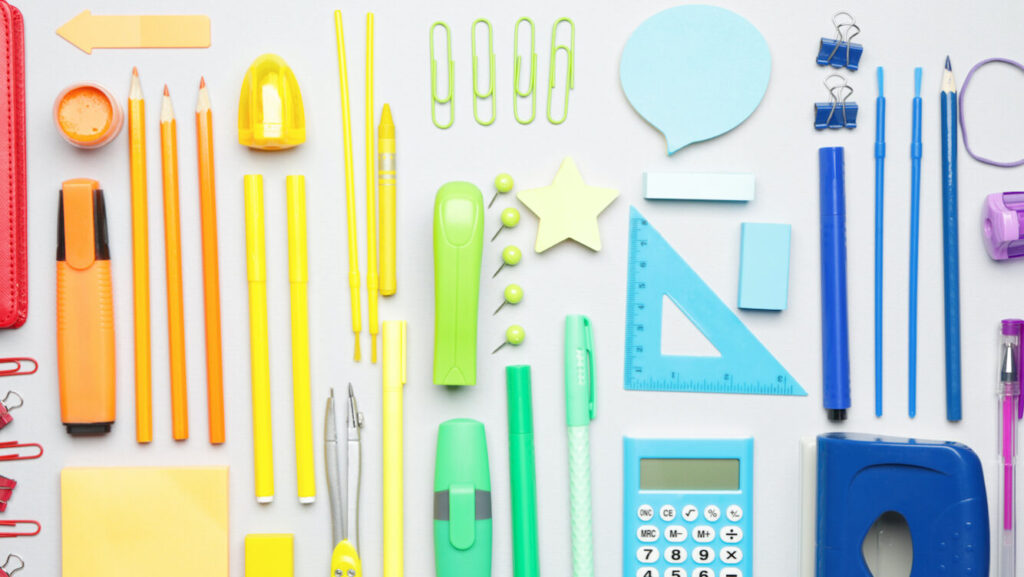 Fournitures scolaires colorées côte à côte sur fond blanc